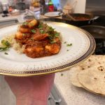 King Prawn Madras served on a fancy plate with homemade flatbreads in the background
