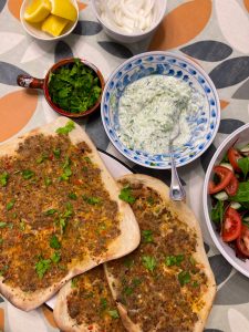 Lamb flatbreads laid out with cucumber dip and freshly chopped coriander